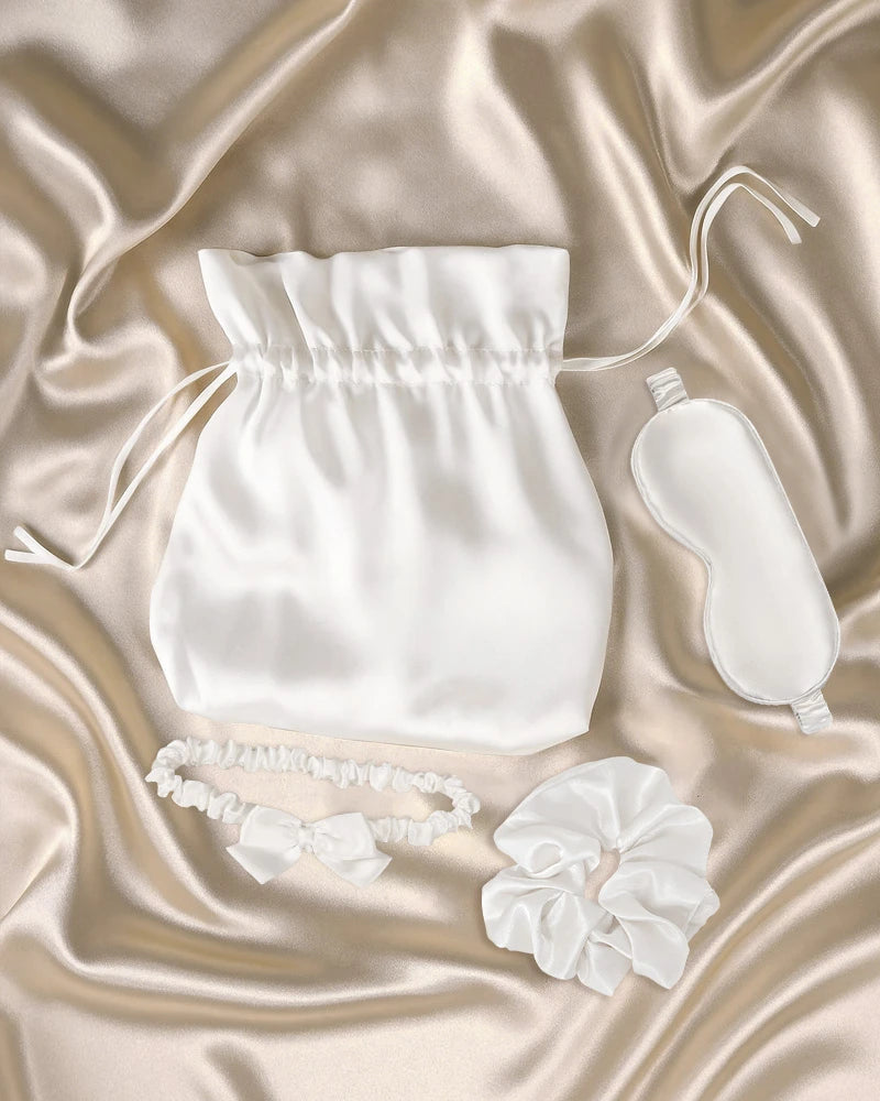 Set of white silk wedding gifts including a pouch, eye mask, headband, and scrunchie.
